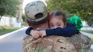 Children of military servicemen joyfully welcomed their fathers back after prolonged military exercises.